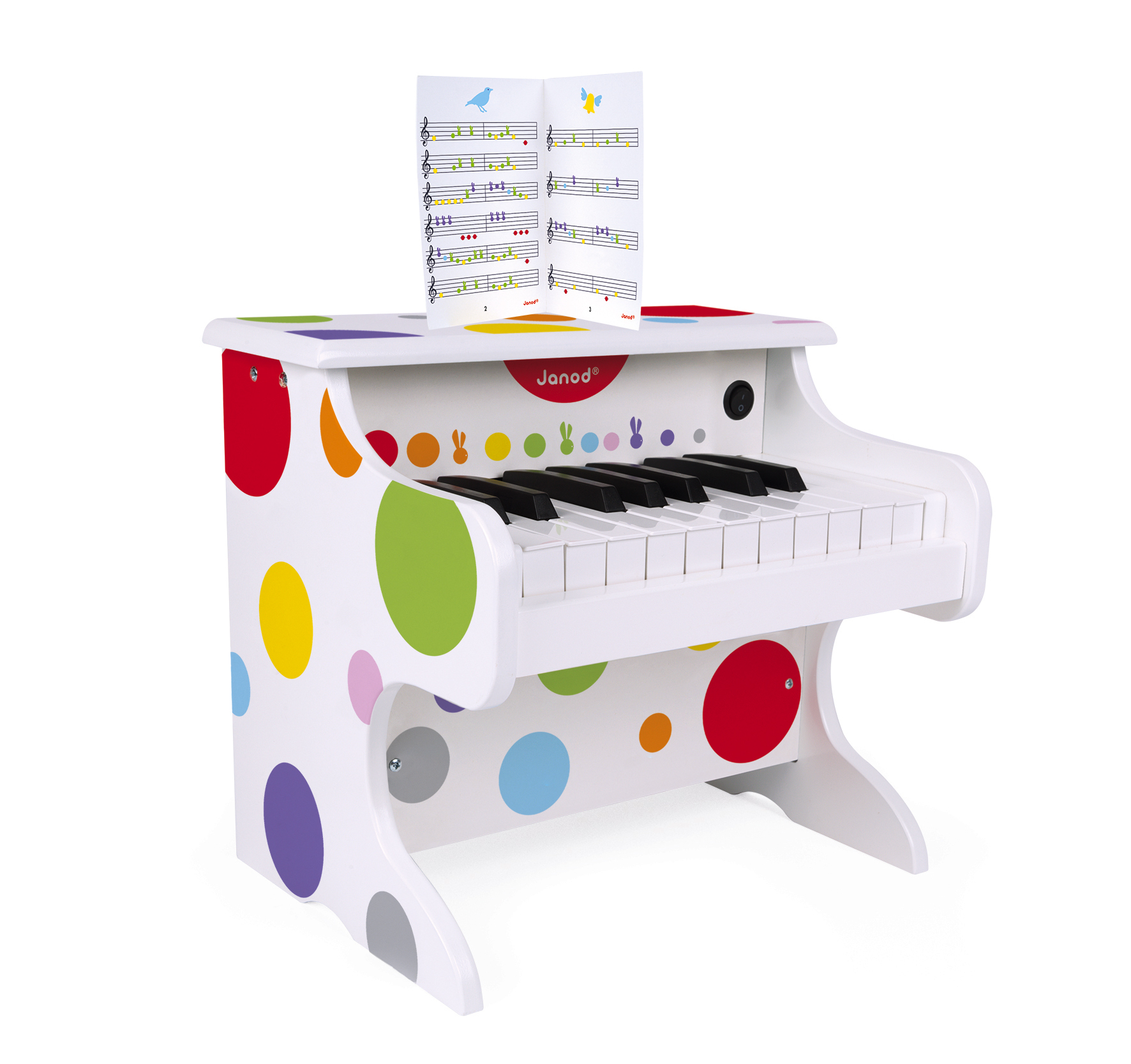 Un piano jouet blanc à pois colorés, touches noires et blanches, et un livre de partitions.