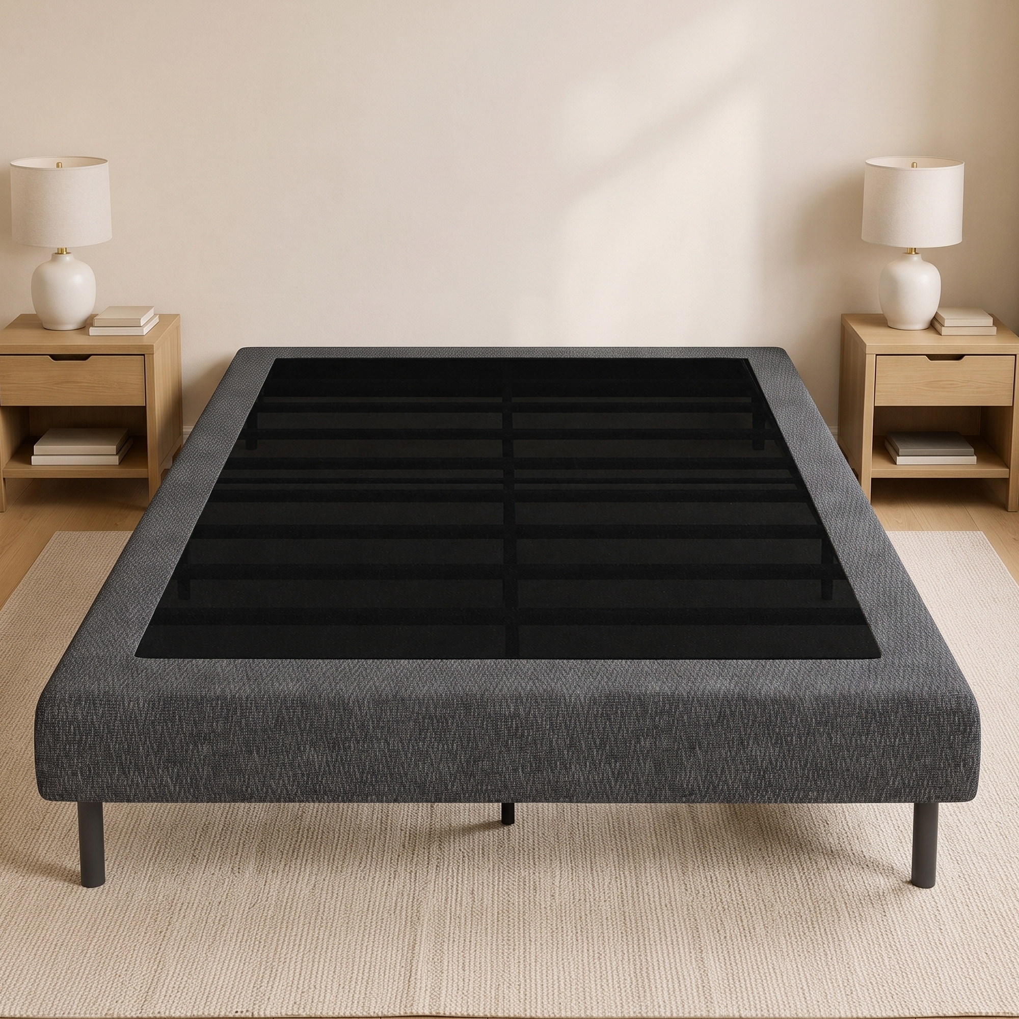 Estructura de cama gris con listones negros, flanqueada por dos mesitas de noche con lámparas contra una pared clara.