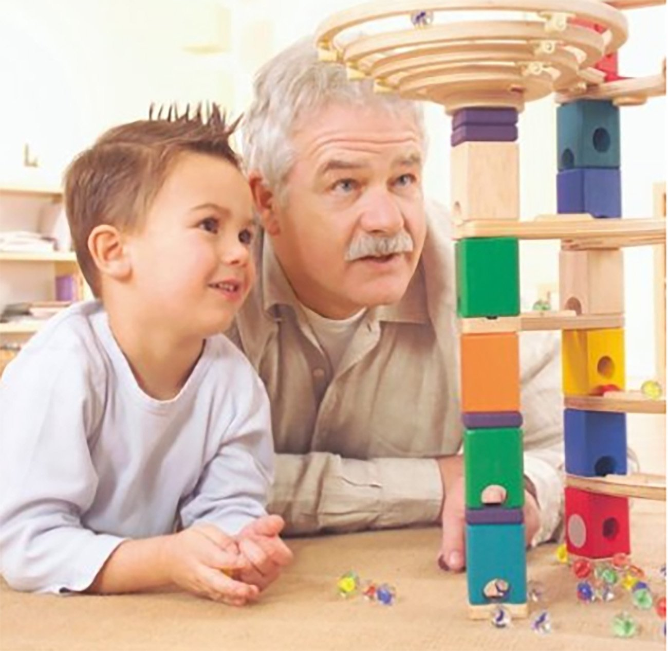 Ein Junge und ein Mann spielen mit einer bunten Murmelbahn aus Holz.
