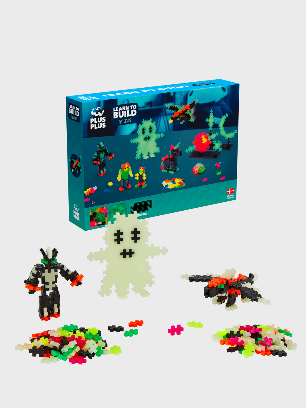 Plus-Plus Leuchtspielzeug-Set mit gebauten Figuren wie Geist, Roboter und Flugzeug sowie losen Teilen.