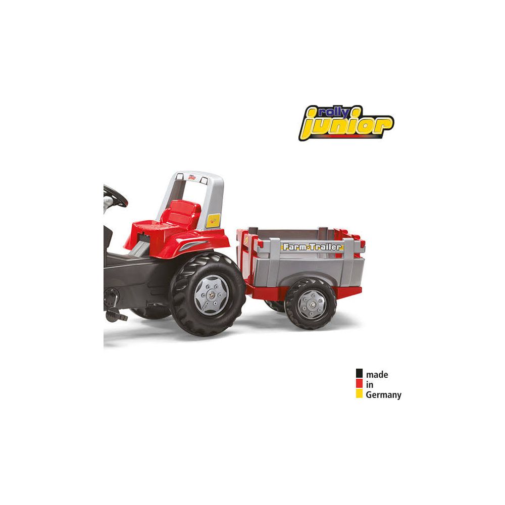 Ein roter Spielzeugtraktor mit Anhänger vor weißem Hintergrund.