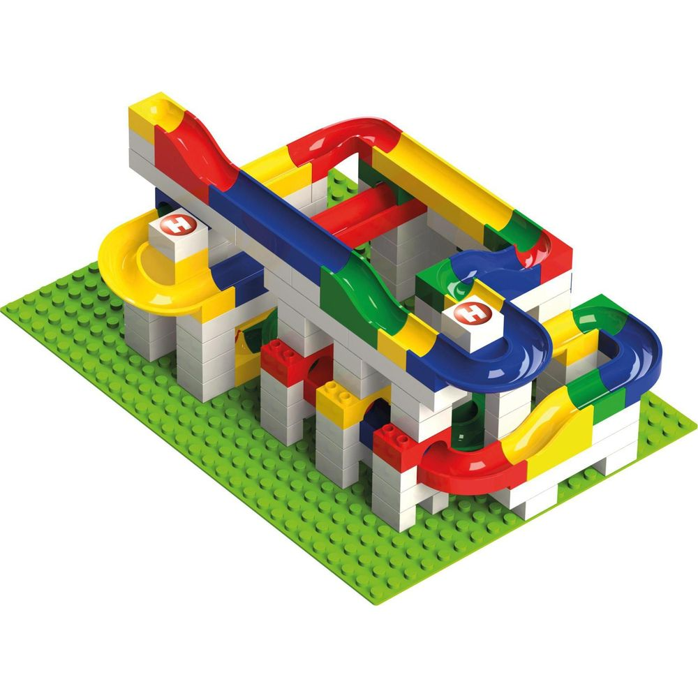 Un circuit de billes coloré construit avec des blocs de construction sur une plaque verte.