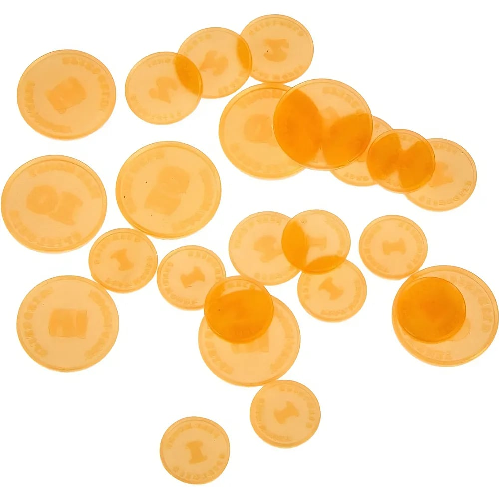 Des pièces de monnaie jouet en plastique orange translucide sur fond blanc.