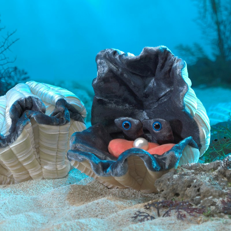 Zwei plüschige Muscheln mit blauen Augen und einer Perle im Sand auf dem Meeresgrund.