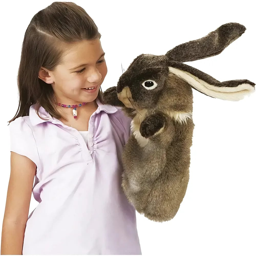 Ein junges Mädchen in einem hellvioletten Hemd hält und betrachtet eine große Stoffhasen-Handpuppe.