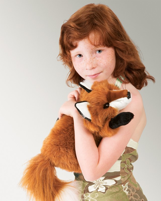 Ragazza dai capelli rossi con lentiggini e top verde abbraccia un peluche.