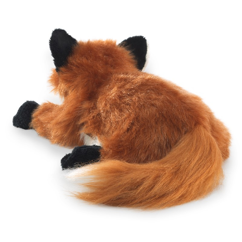 Una volpe di peluche vista da dietro, con coda folta e zampe e orecchie nere, su sfondo bianco.