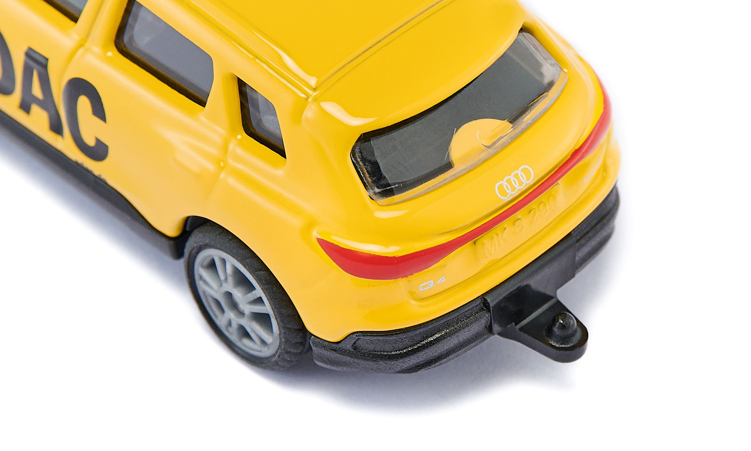 Gros plan d'une voiture jouet jaune avec attelage noir, logo Audi et lettres sur fond blanc.