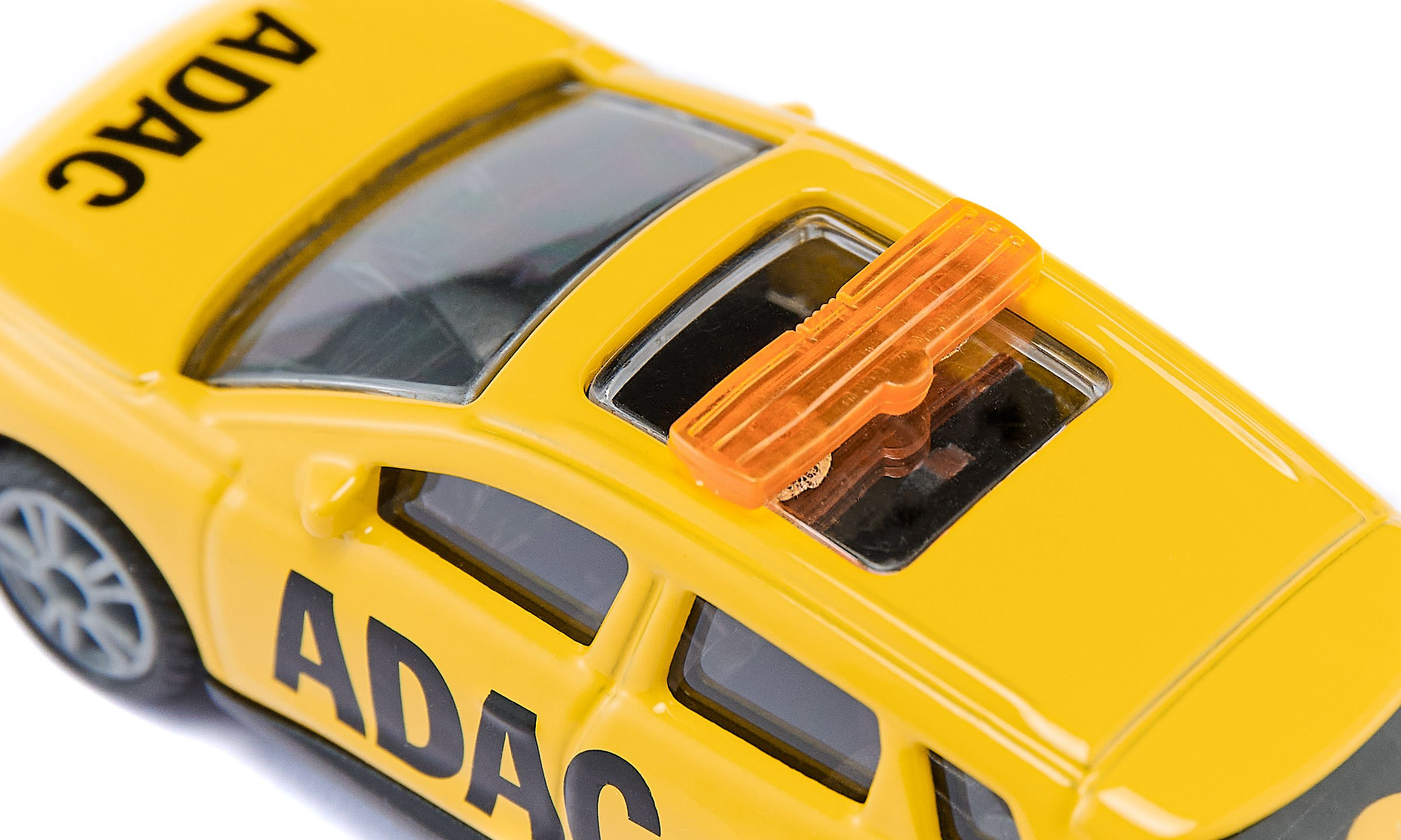 Une voiture jouet ADAC jaune vue du dessus, avec un feu de toit orange sur fond blanc.
