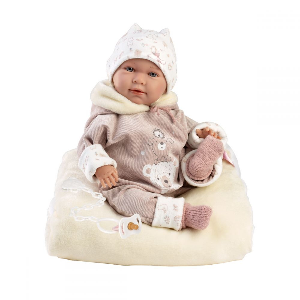 Reborn-Puppe mit beigem Bären-Strampler und Mütze sitzt auf einer Decke mit Schnuller.