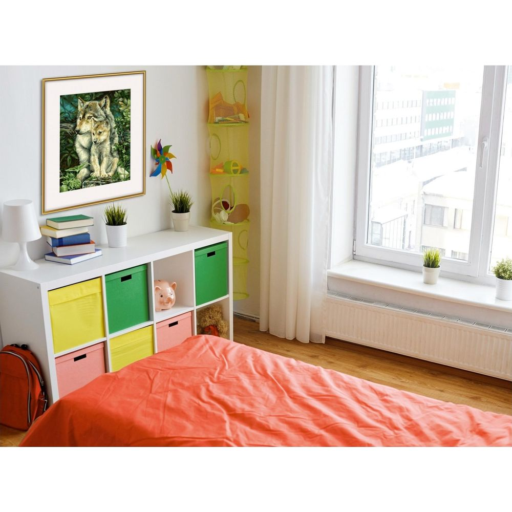 Ein Kinderzimmer mit weißem Regal, farbigen Boxen, rotem Bett und einem gerahmten Wolfsbild an der Wand.
