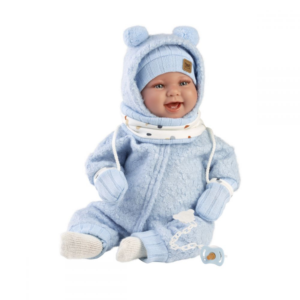Una bambola sorridente in tuta invernale blu, giacca con cappuccio, guanti e calzini bianchi su sfondo bianco.