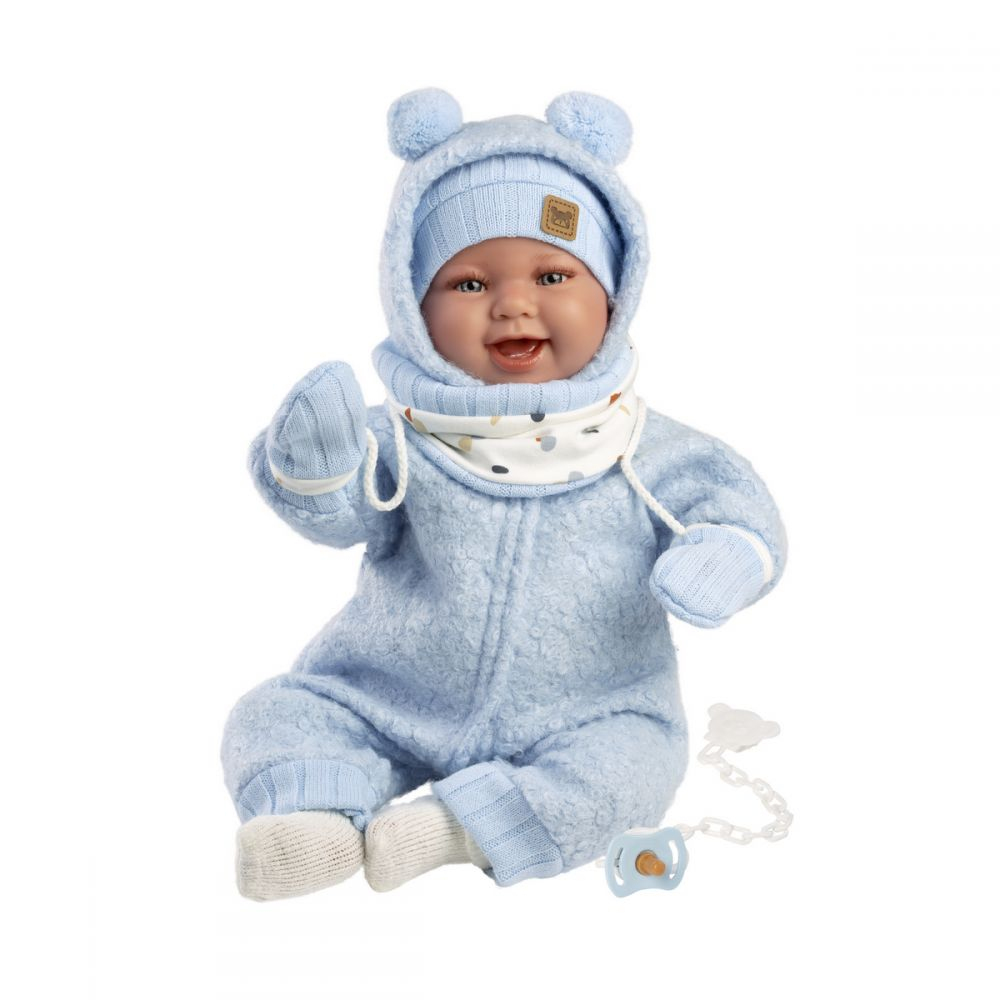 Bambola sorridente con vestiti invernali blu soffici, cappello, sciarpa e ciuccio.