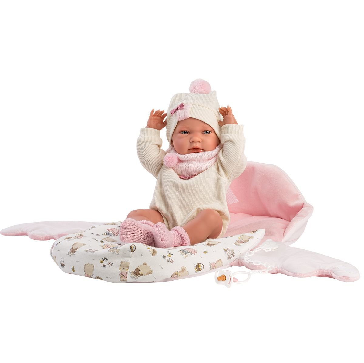 Bambola Reborn in abito bianco e cappello, seduta su una coperta rosa con motivo di orsetti.