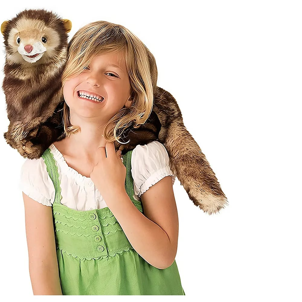 Une fille blonde souriante en robe verte porte une marionnette furet en peluche sur ses épaules.