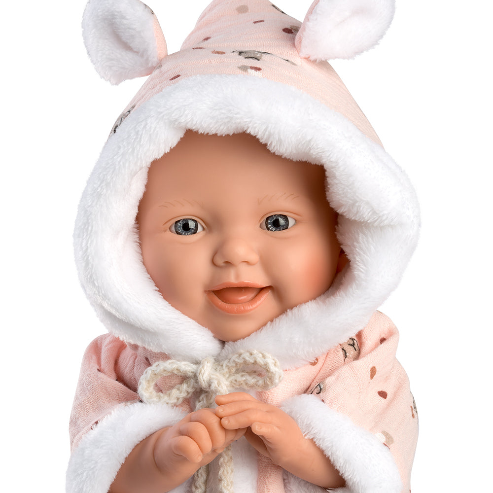 Una bambola con cappotto rosa con cappuccio e orecchie da coniglio, sorridente su sfondo bianco.