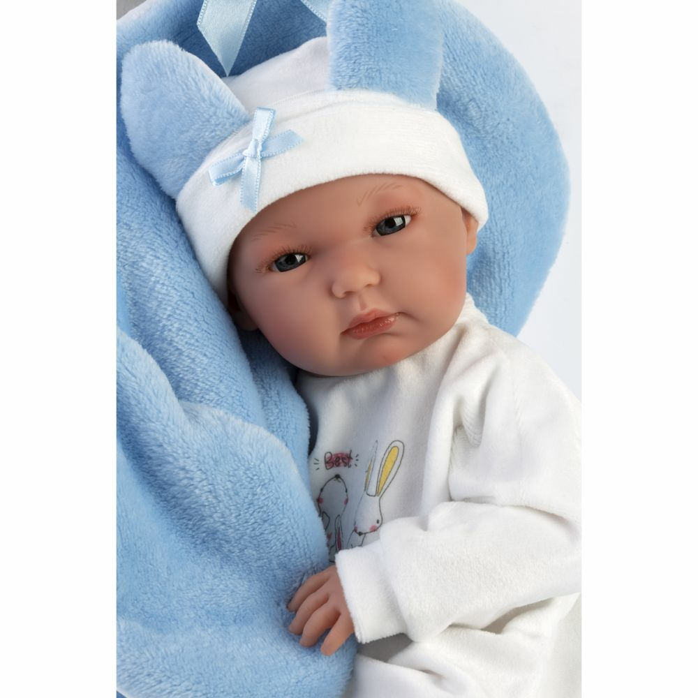Una bambola con vestiti bianchi e blu avvolta in una morbida coperta blu.
