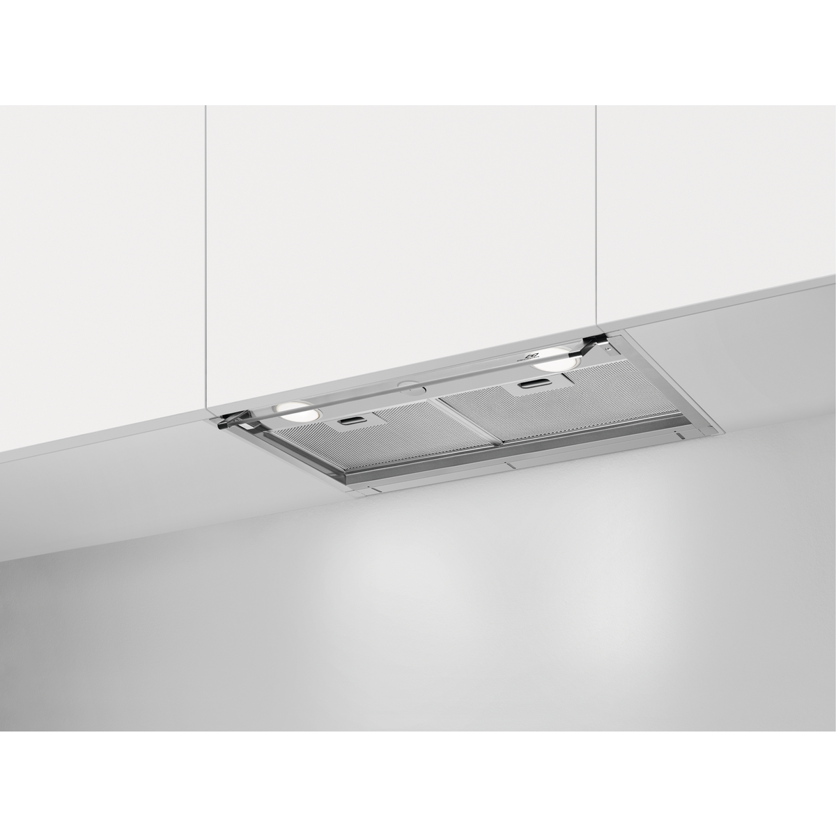 Una campana extractora plateada empotrada bajo armarios de cocina blancos, con dos luces encendidas.