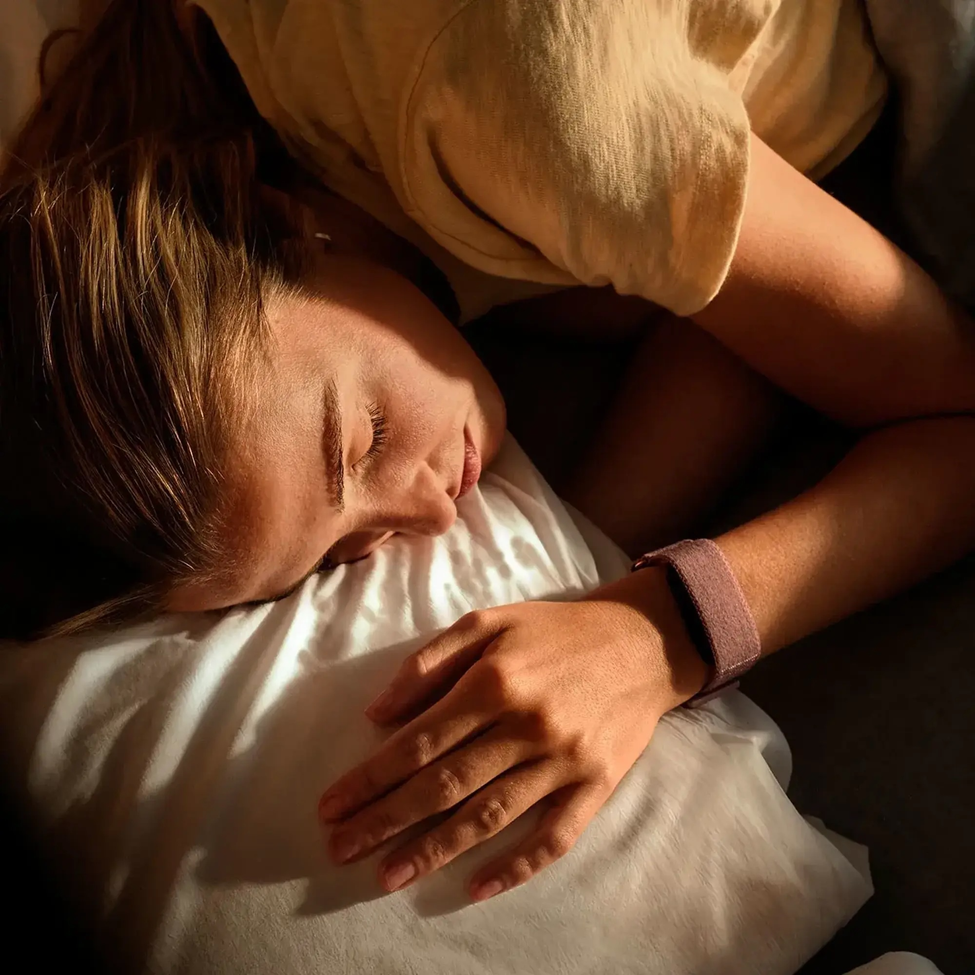 Une femme dort paisiblement dans son lit, la tête posée sur un oreiller blanc.