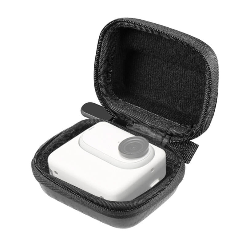Una piccola fotocamera bianca con obiettivo rotondo all'interno di una custodia rigida nera aperta.