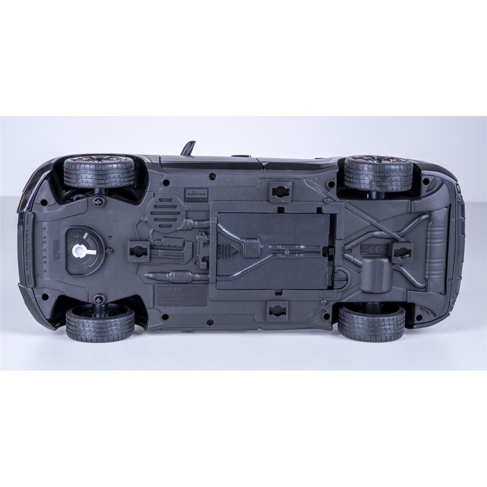 Unteransicht eines schwarzen Spielzeugautofahrgestells mit sichtbaren Rädern, Auspuffrohren und Batteriefach.