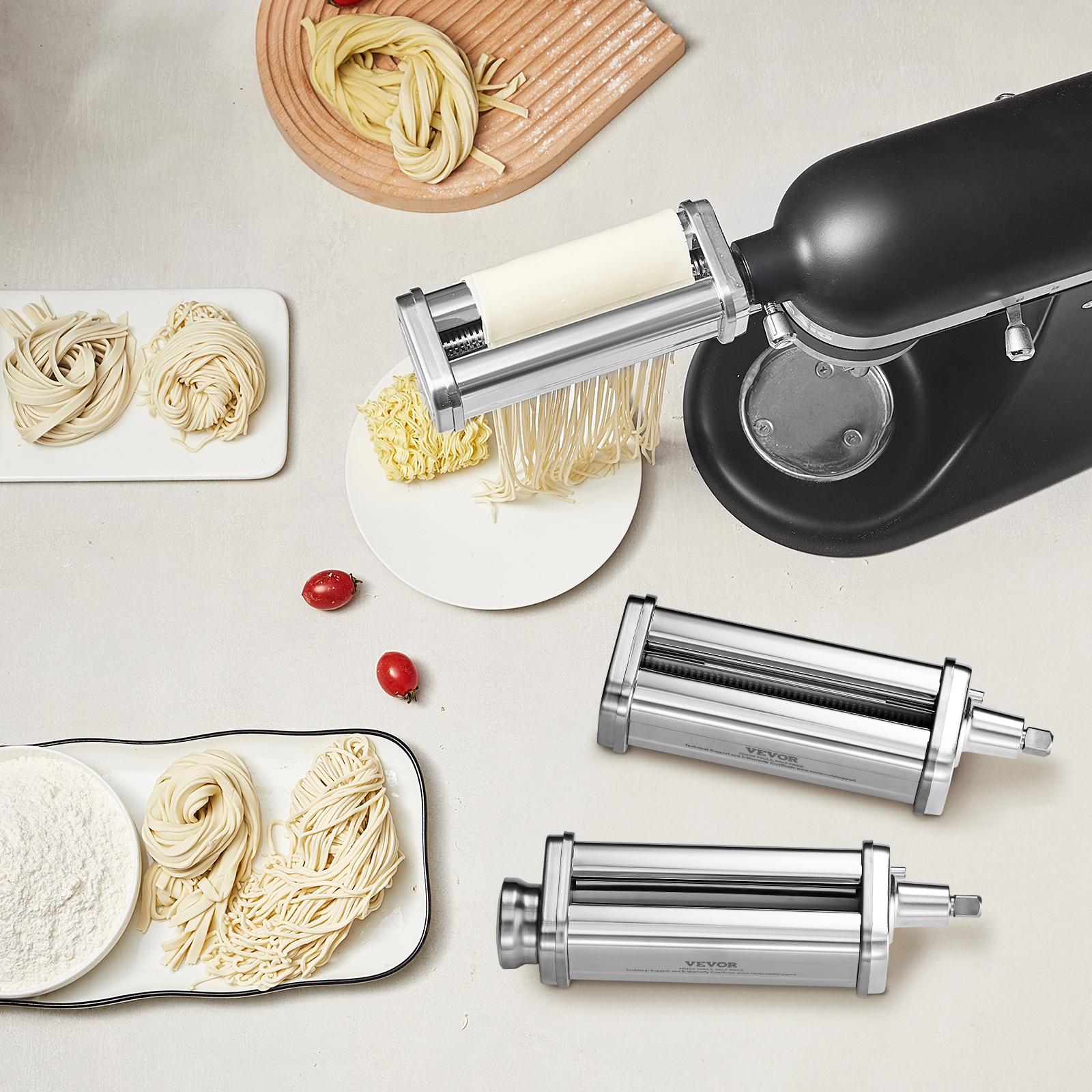 Una batidora de pie negra con accesorio para pasta, fideos frescos, harina y dos accesorios de acero adicionales.