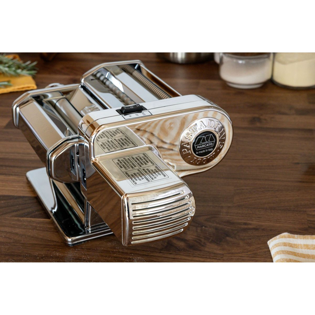 Una macchina per pasta argentata e lucida con motore su una superficie di legno scuro.
