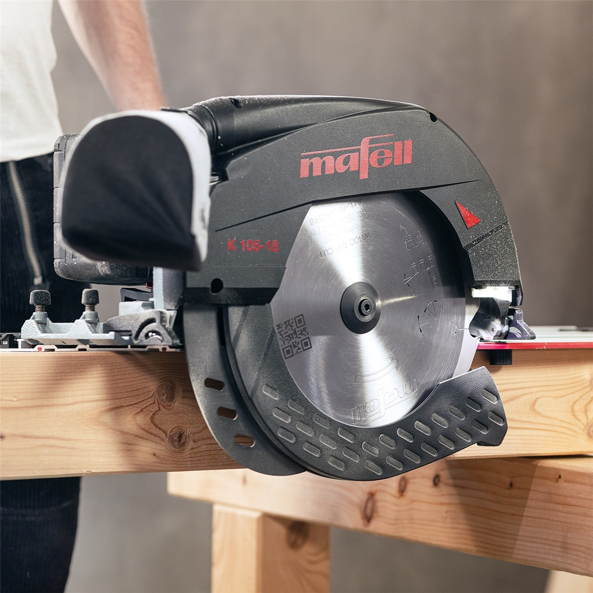 Eine Mafell K 105-18 Handkreissäge schneidet Holz auf einer Werkbank.