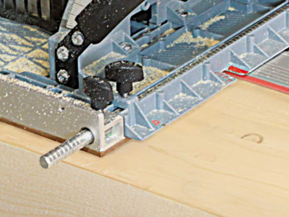 Blaue Werkzeugführung aus Plastik mit schwarzen Knöpfen auf hellem Holz.