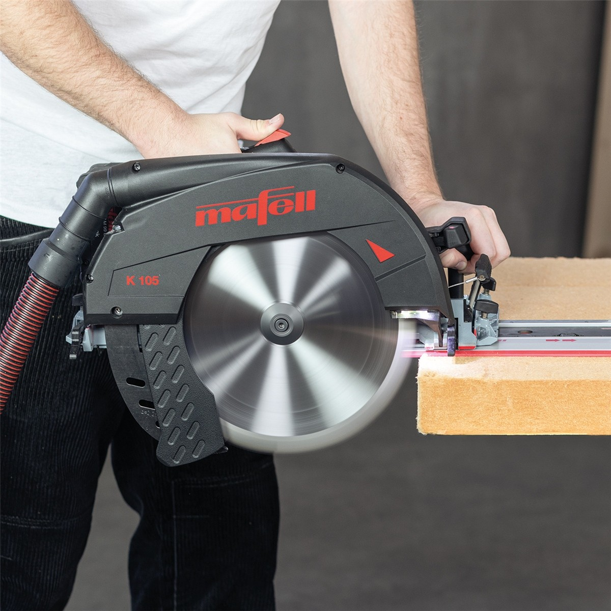 Ein Handwerker nutzt eine Mafell K 105 Kreissäge mit Absaugschlauch, um ein Holzstück zu schneiden.