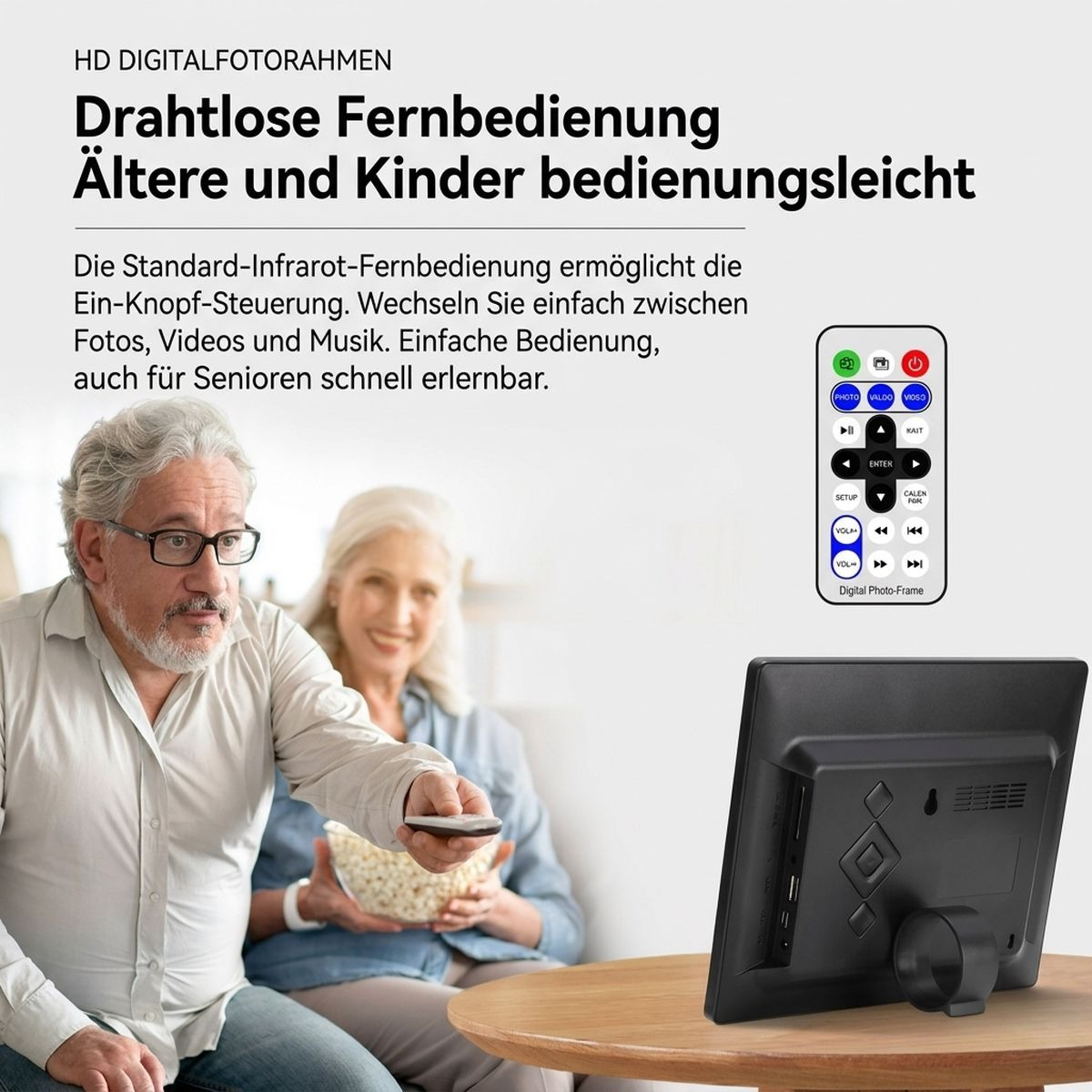 Älterer Mann bedient mit Fernbedienung einen digitalen Fotorahmen, während eine Frau im Hintergrund Popcorn isst.
