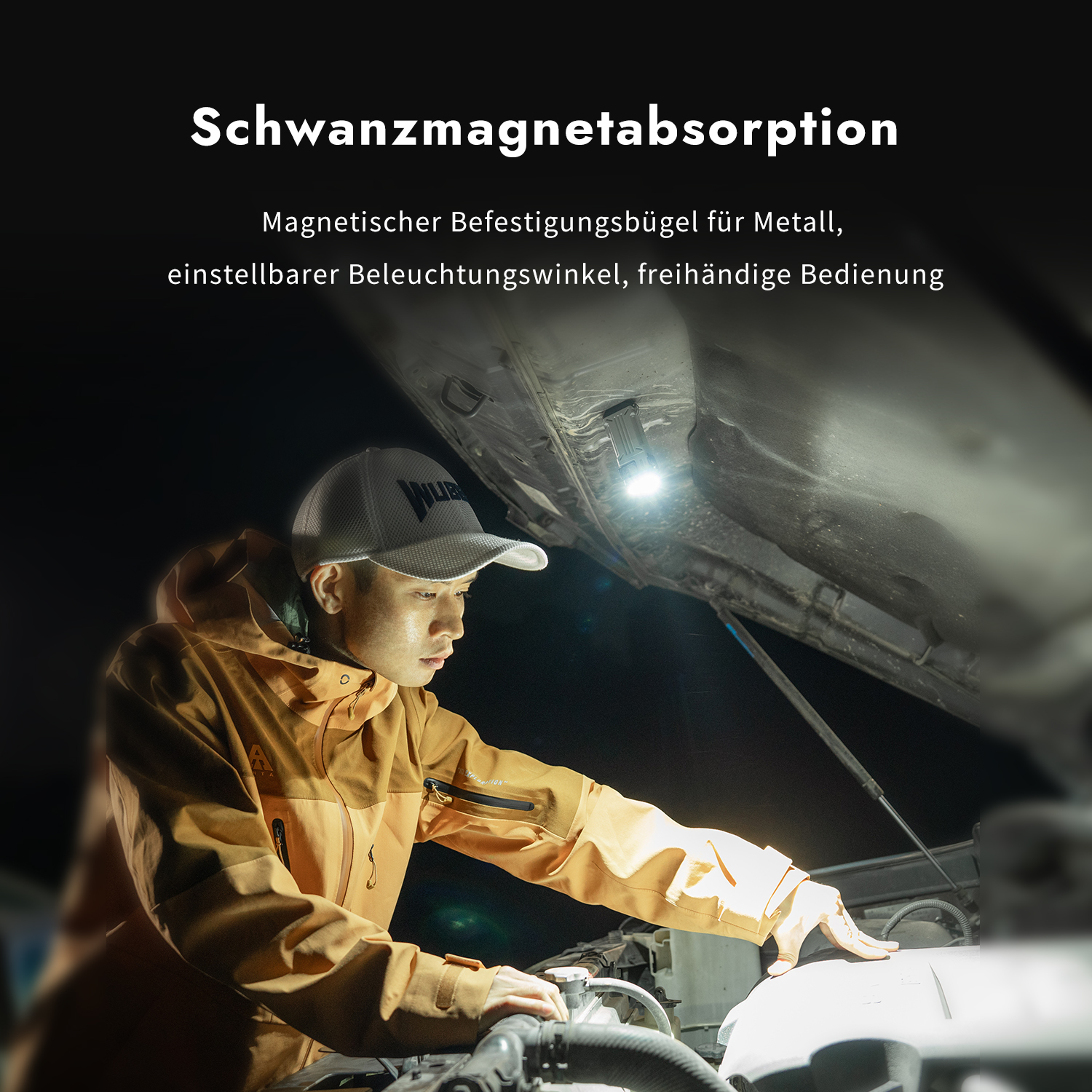 Ein Mann mit Kappe und Jacke repariert nachts ein Auto mit einer magnetischen Lampe unter der Haube.