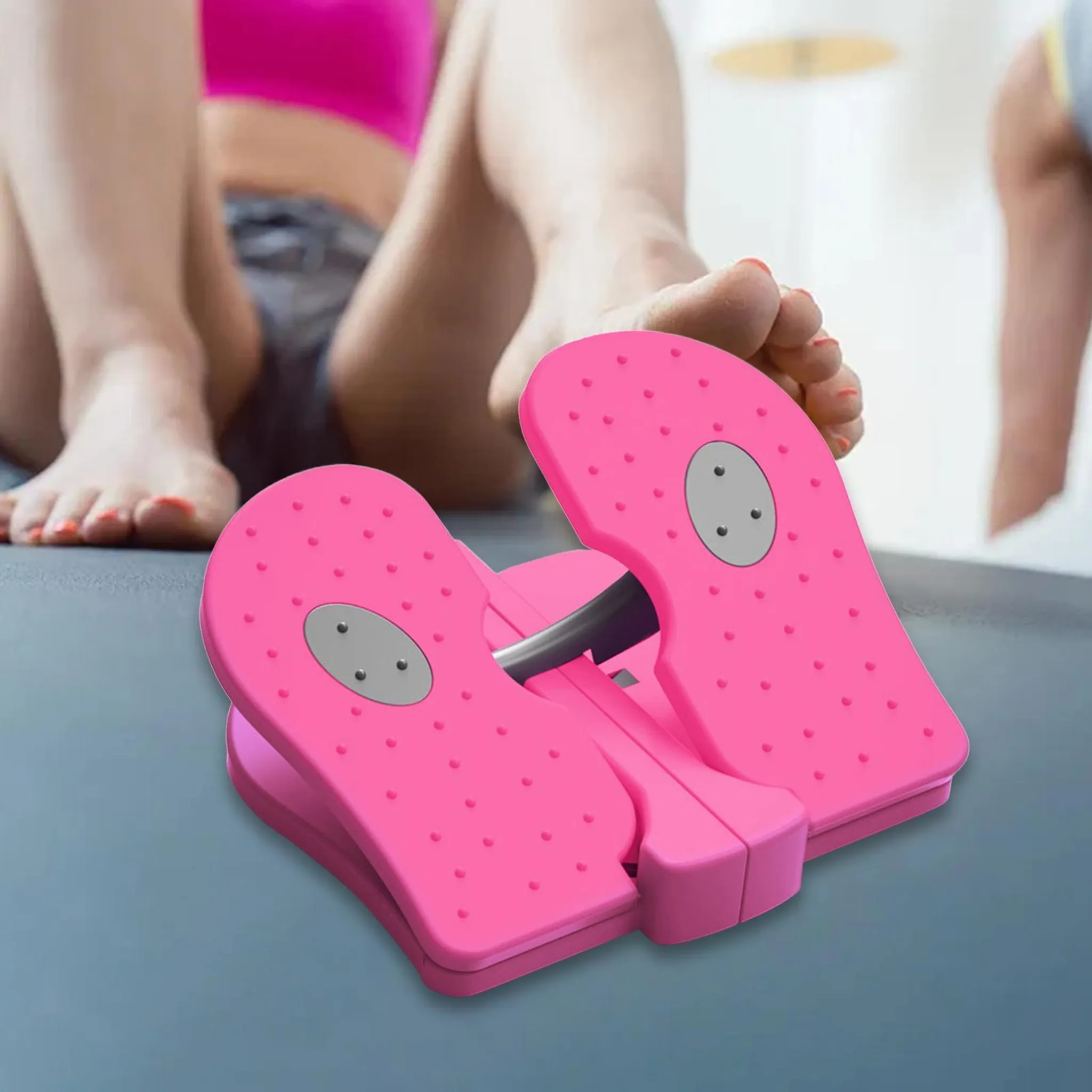 Eine Person benutzt einen rosa Fußtrainer auf einer Matte mit nackten Fü ßen auf den strukturierten Pedalen.