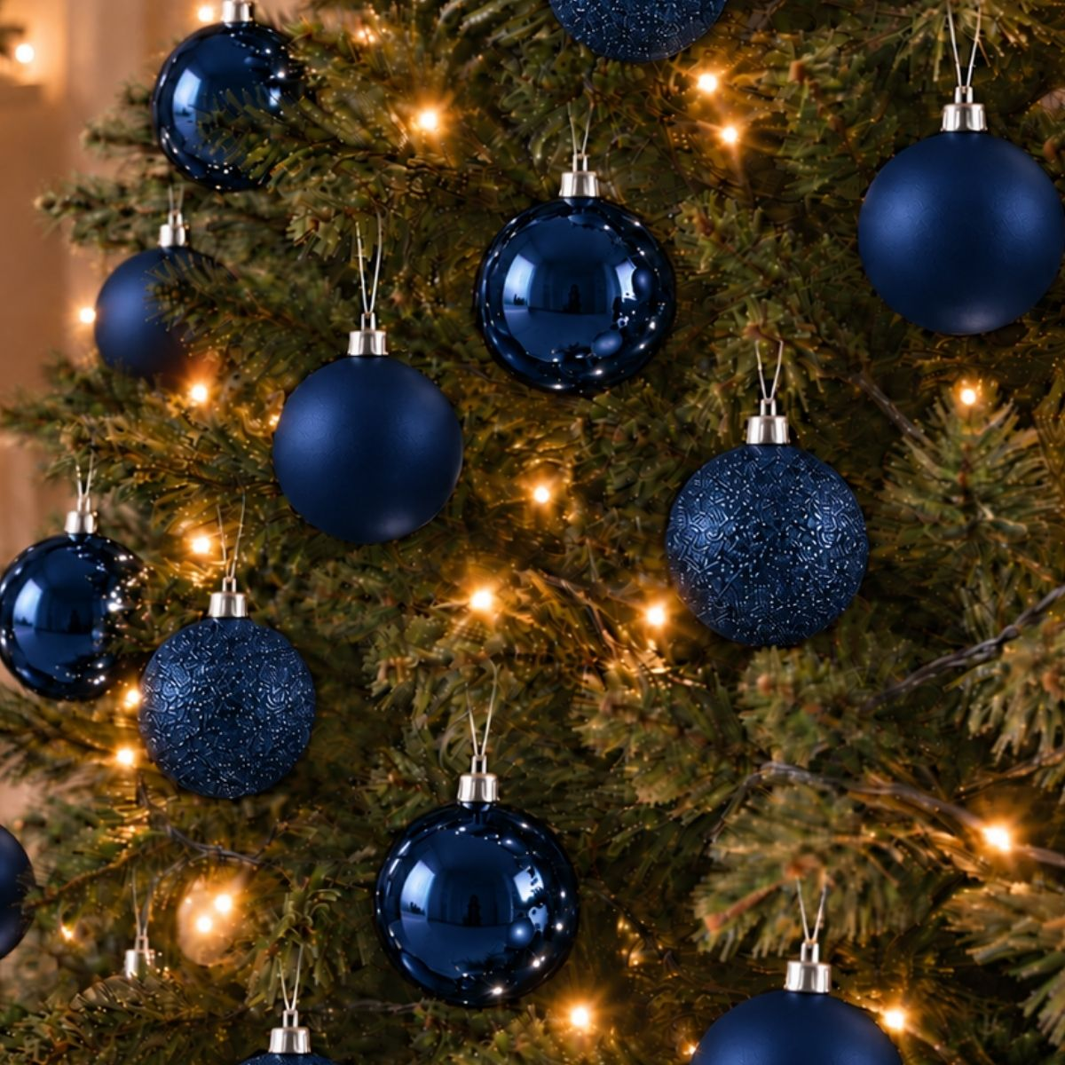Gros plan d'un sapin de Noël décoré de boules bleues brillantes et mates et de guirlandes lumineuses.