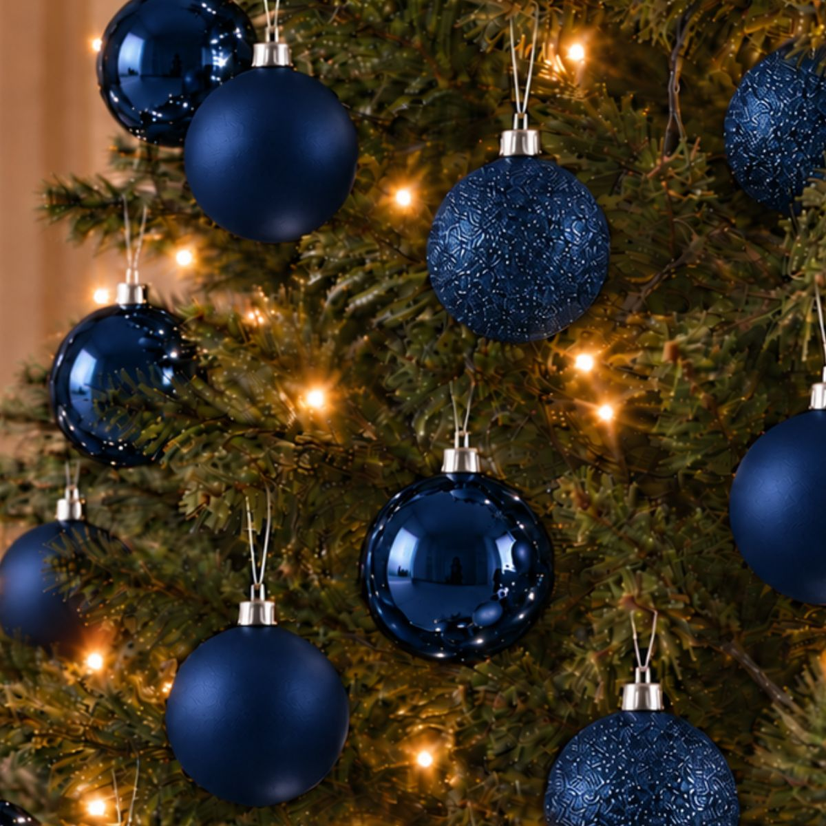 Des boules de Noël bleu foncé brillantes et mates sont suspendues à un sapin.