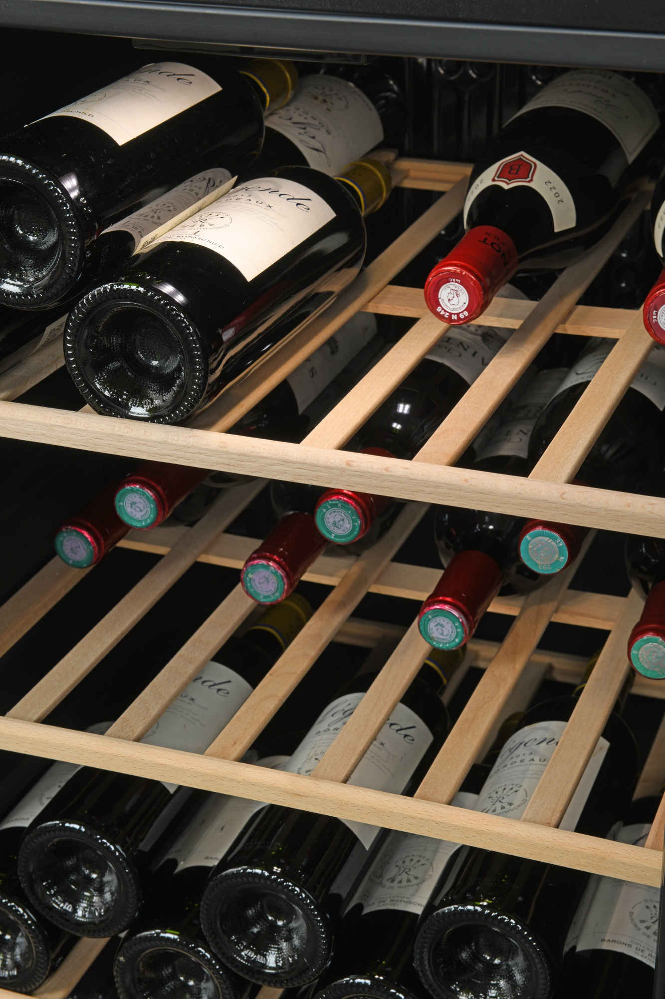 Botellero en una vinoteca lleno de varias botellas de vino tinto.