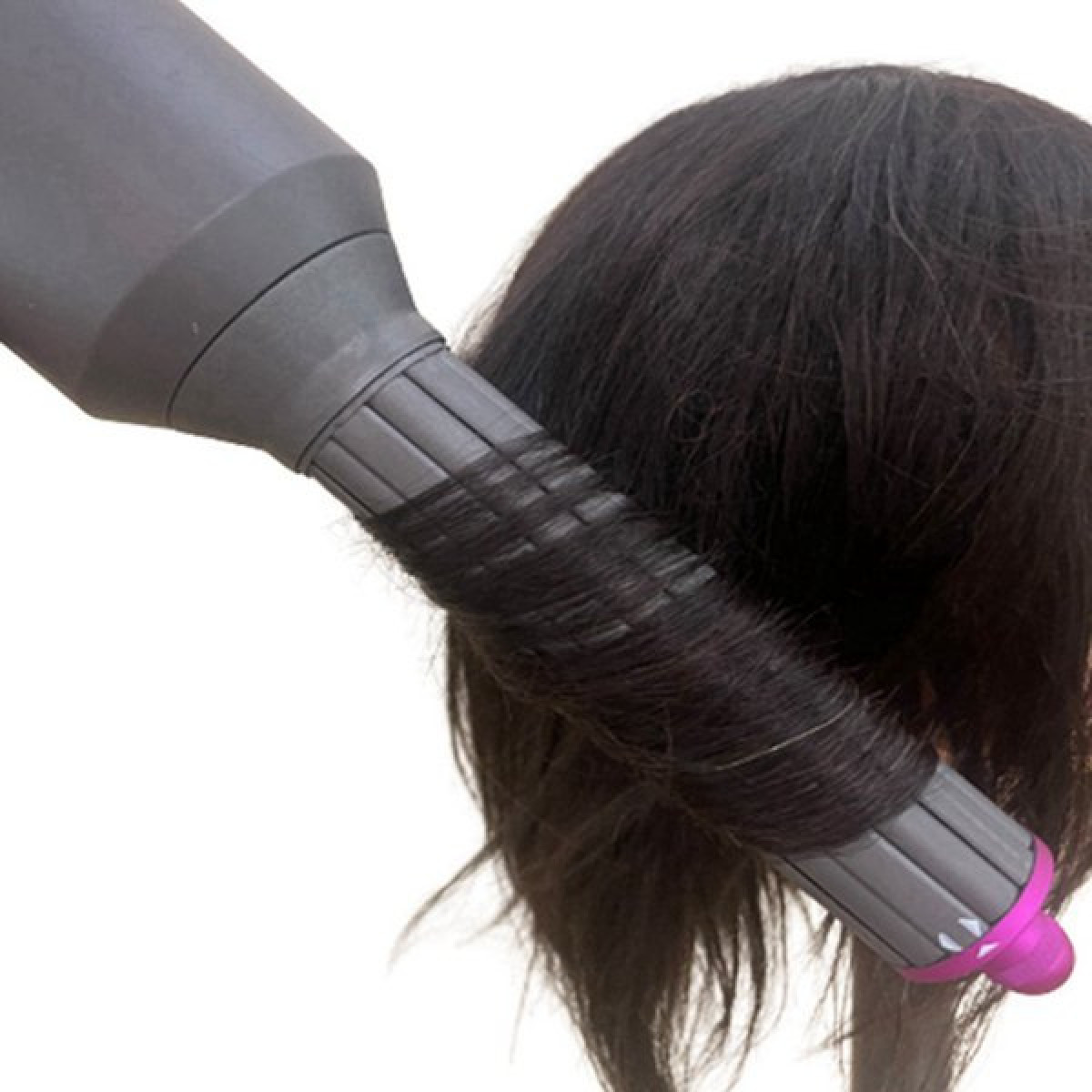 Un ferro arricciacapelli scuro avvolge capelli scuri su un accessorio.