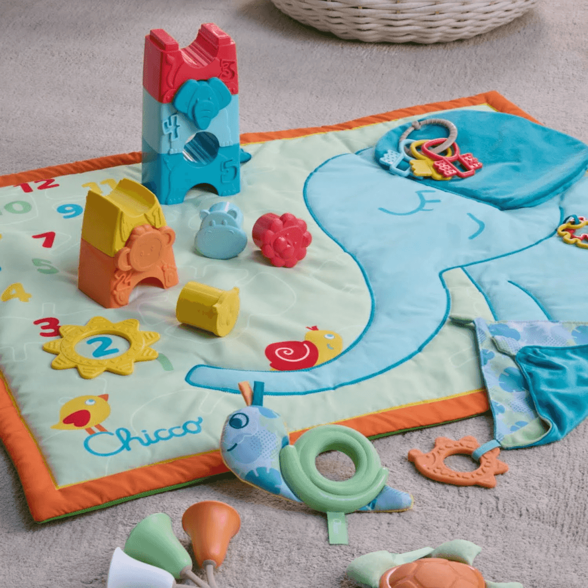 Alfombra de juegos colorida para bebé Chicco con juguetes y un diseño de elefante.