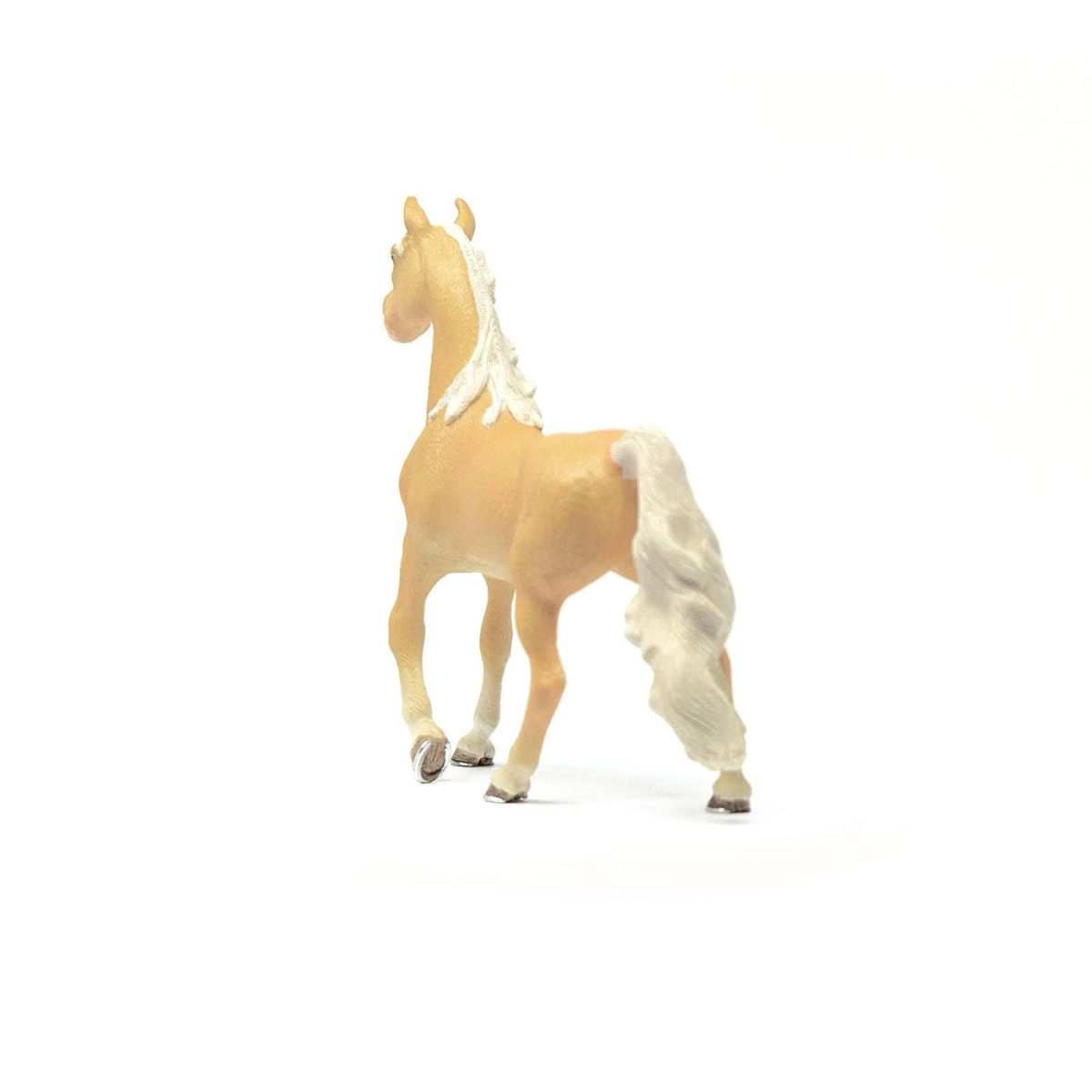 Eine Palomino-Pferdefigur aus Spielzeug mit weißer Mähne und Schweif von hinten vor weißem Hintergrund.