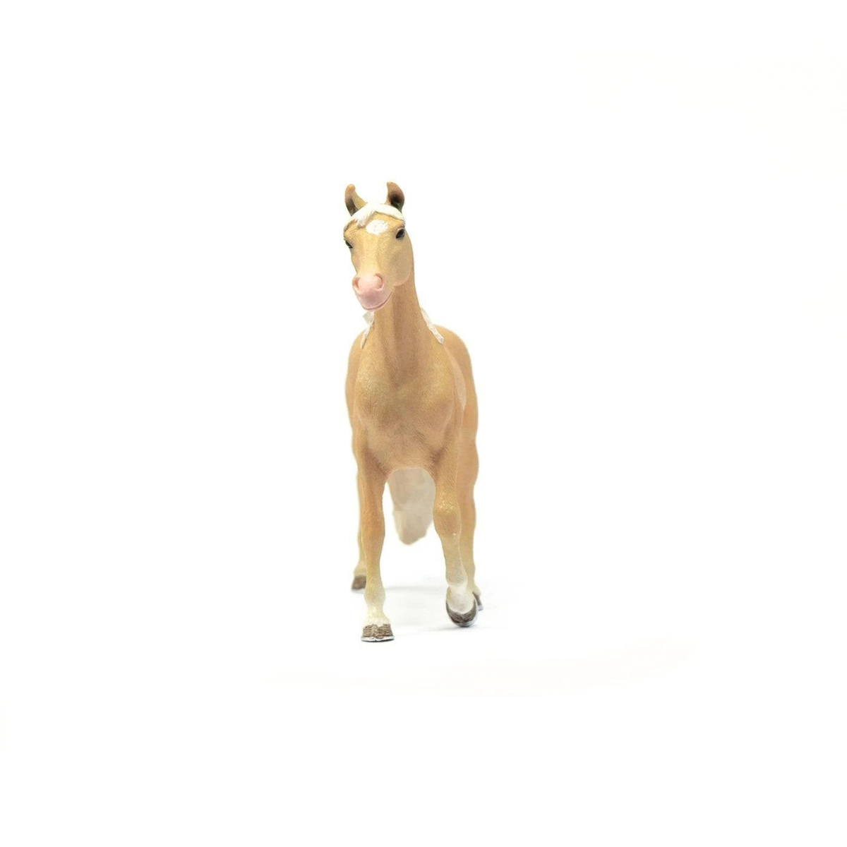 Eine Spielzeug-Palomino-Pferdefigur mit weißer Mähne und Schweif steht vor einem weißen Hintergrund.