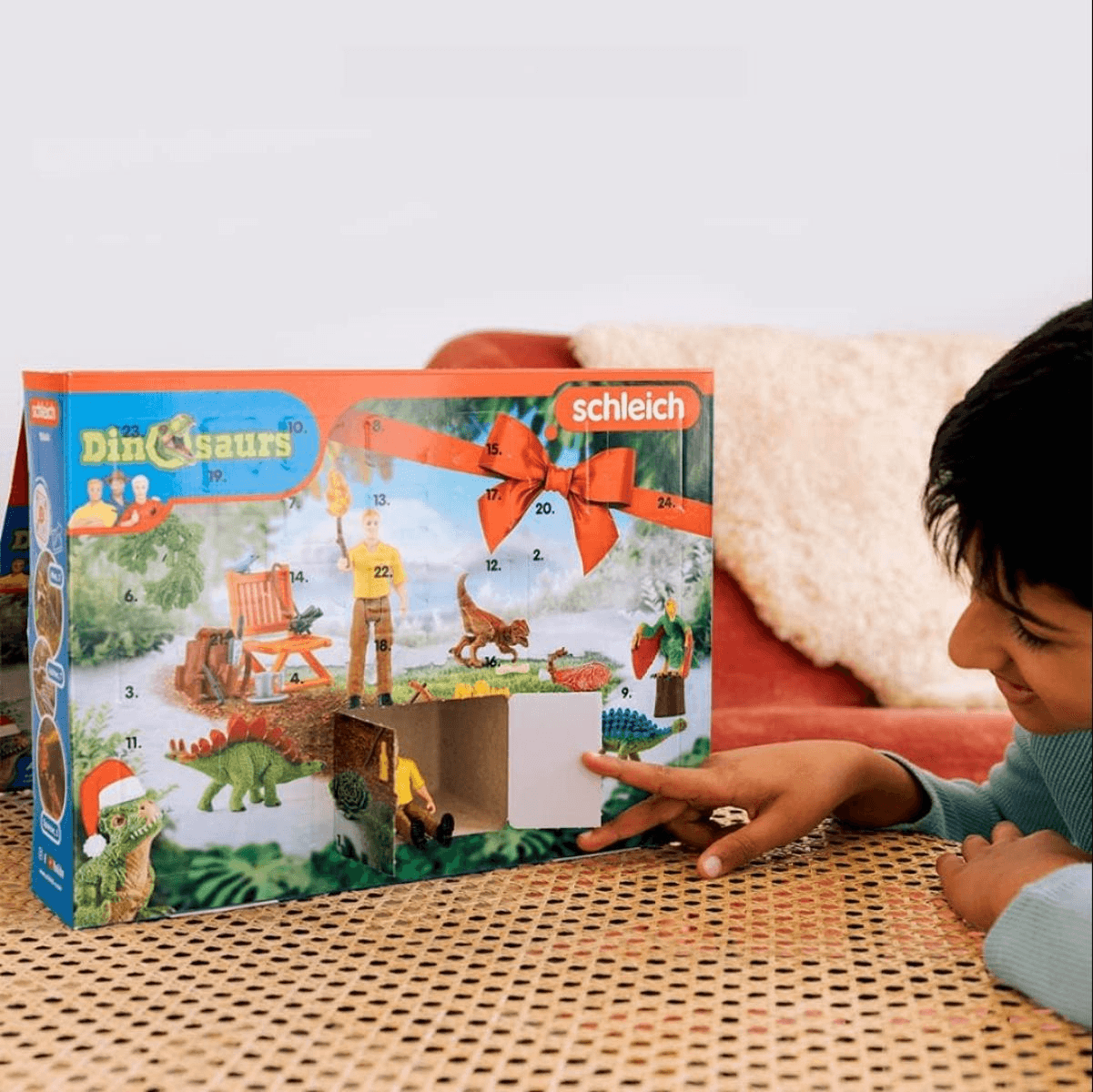 Un bambino apre una porticina di un calendario dell'avvento Schleich Dinosaurs.