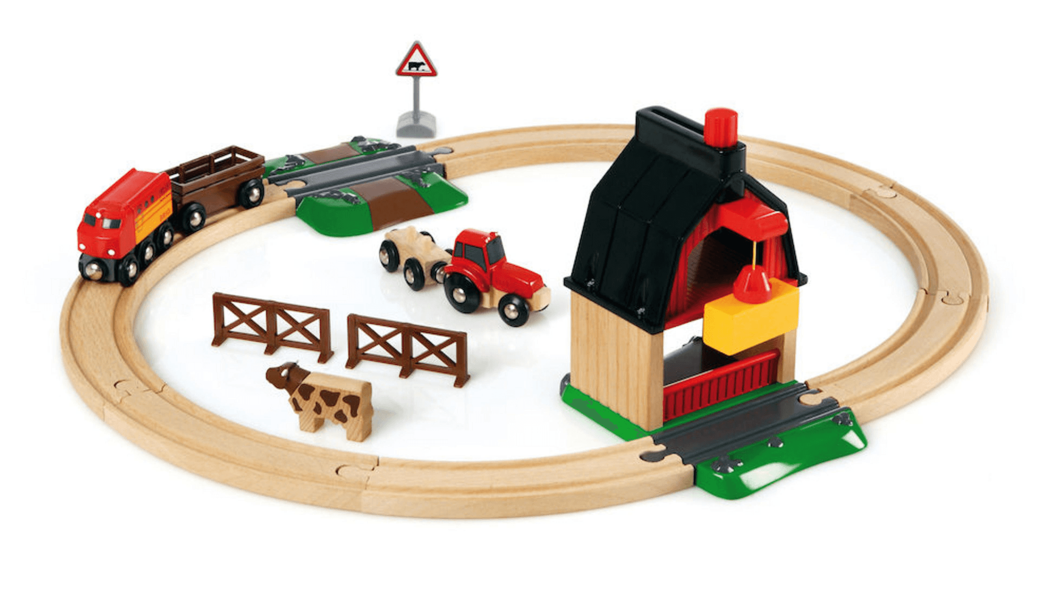 Tren de juguete de madera con tren rojo, vías, granero, tractor rojo, cerca y una vaca sobre fondo blanco.