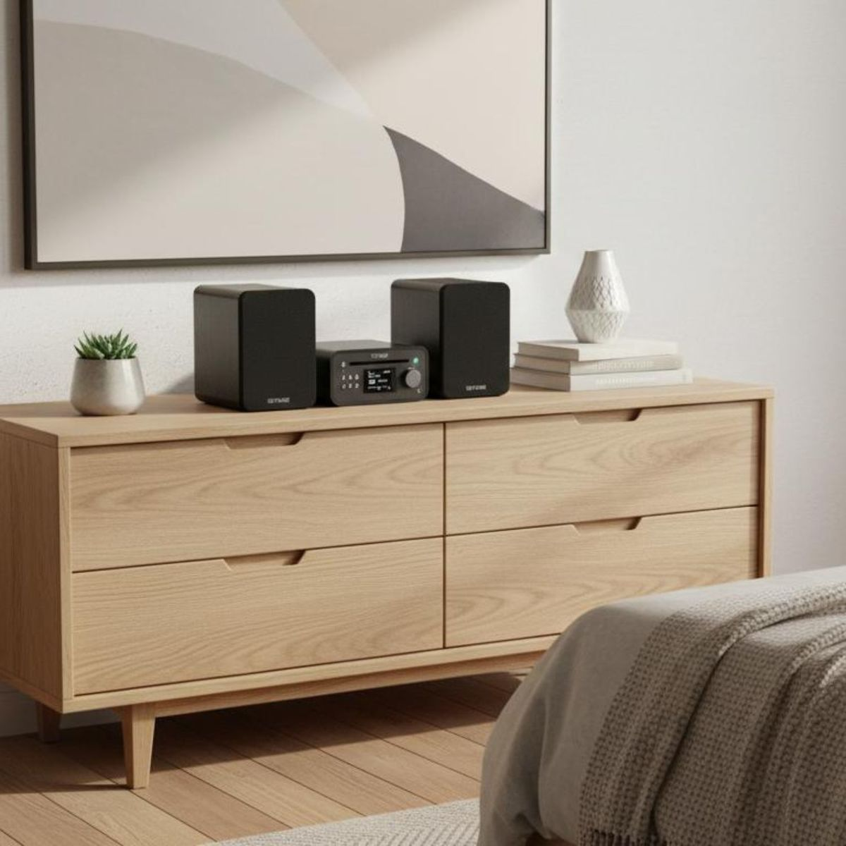 Ein Holzschrank mit Lautsprechern, Büchern und Pflanze, darüber ein gerahmtes Bild.