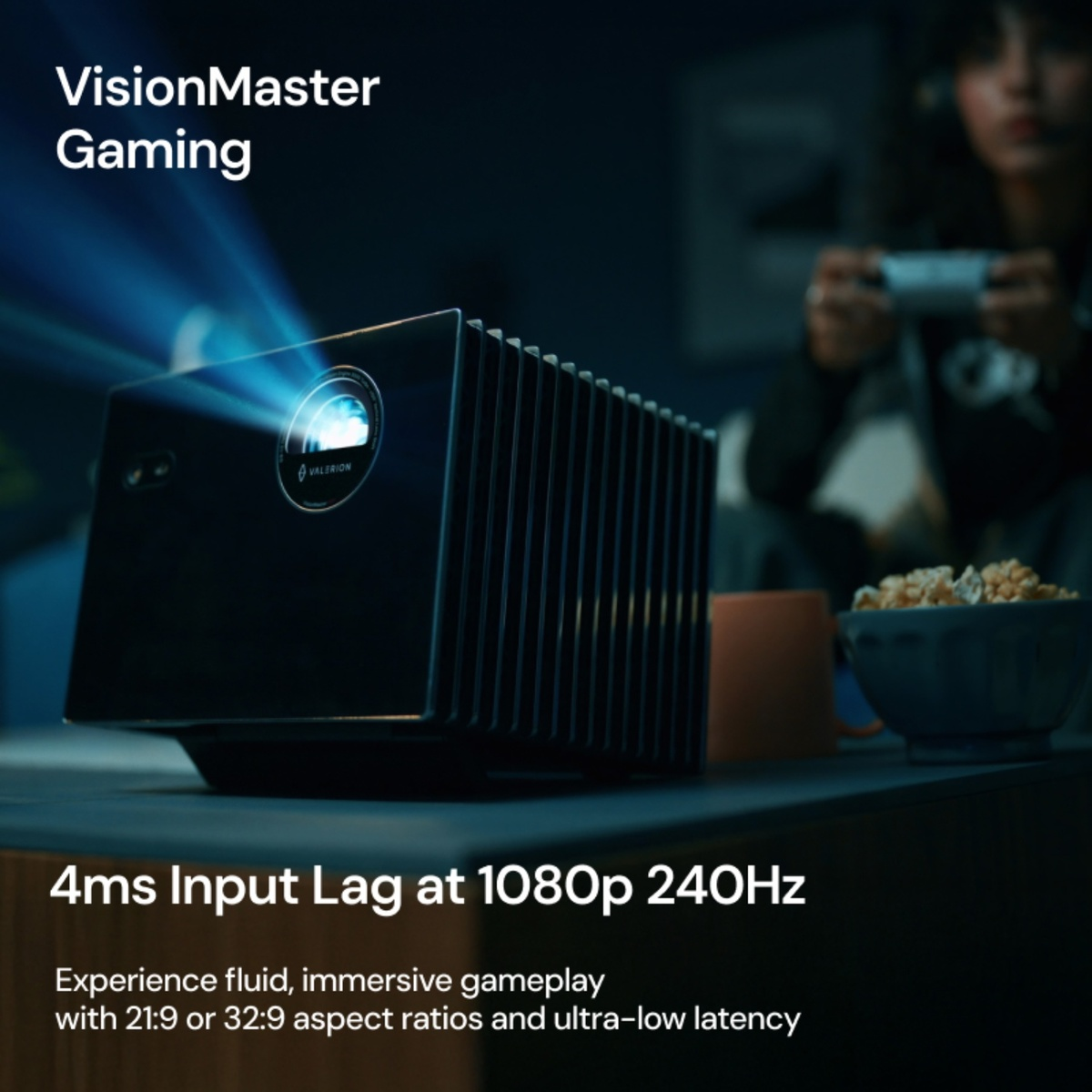 Ein schwarzer Gaming-Projektor steht auf einem Tisch, während im Hintergrund jemand mit einem Controller spielt.