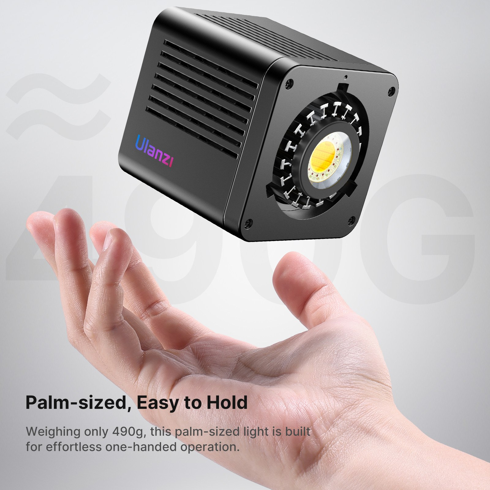 Una mano sostiene una pequeña luz LED cúbica negra de Ulanzi sobre un fondo gris claro con texto.