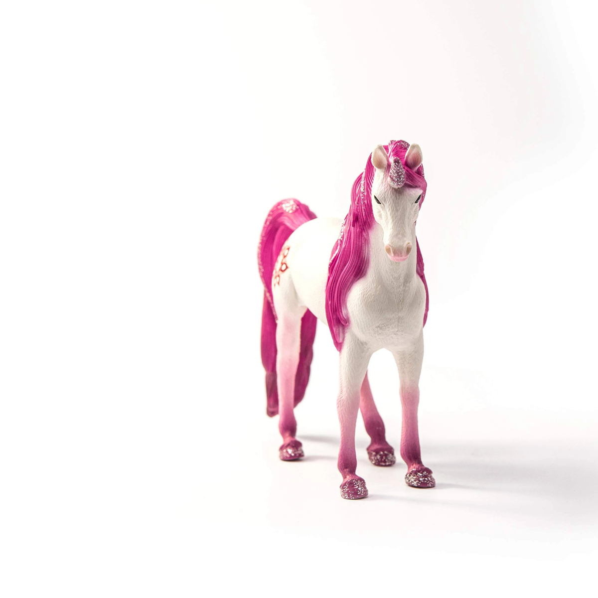 Una figura de unicornio blanco con crin, cola y detalles brillantes de color rosa vibrante sobre fondo claro.