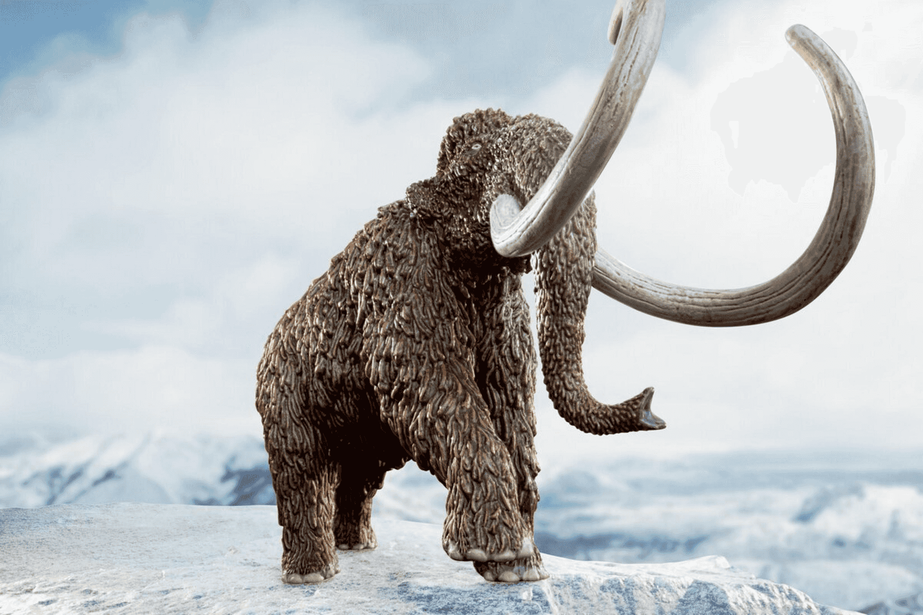 Un mamut peludo con grandes colmillos curvos se encuentra en un acantilado nevado.