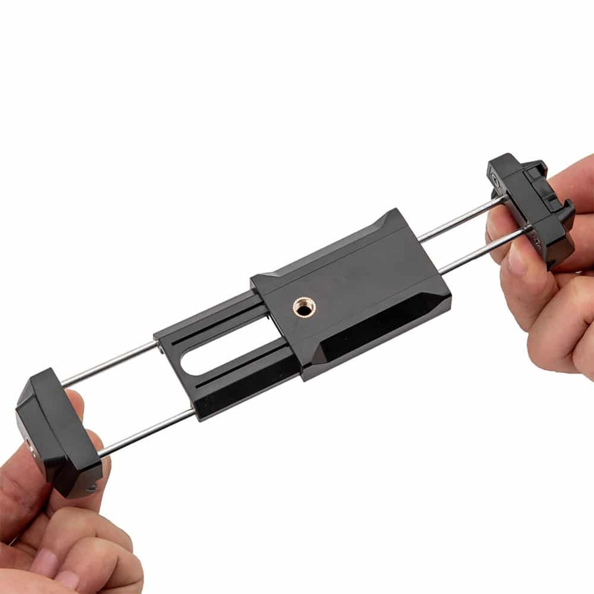 Des mains tiennent un support de téléphone noir réglable avec des tiges métalliques.