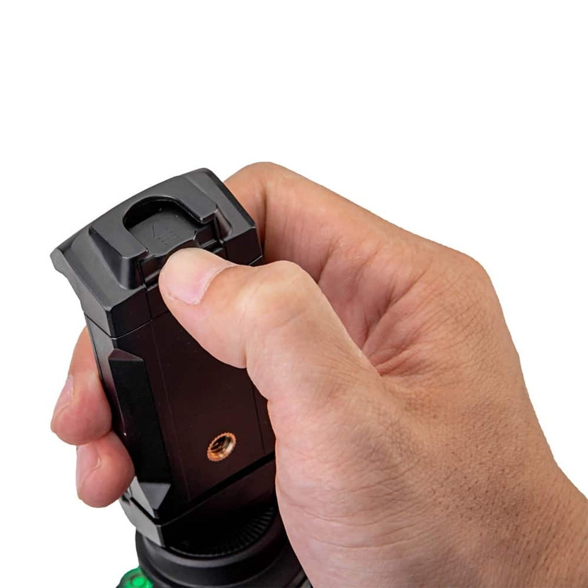 Une main appuie sur le bouton de déverrouillage d'un appareil en plastique noir sur fond blanc.