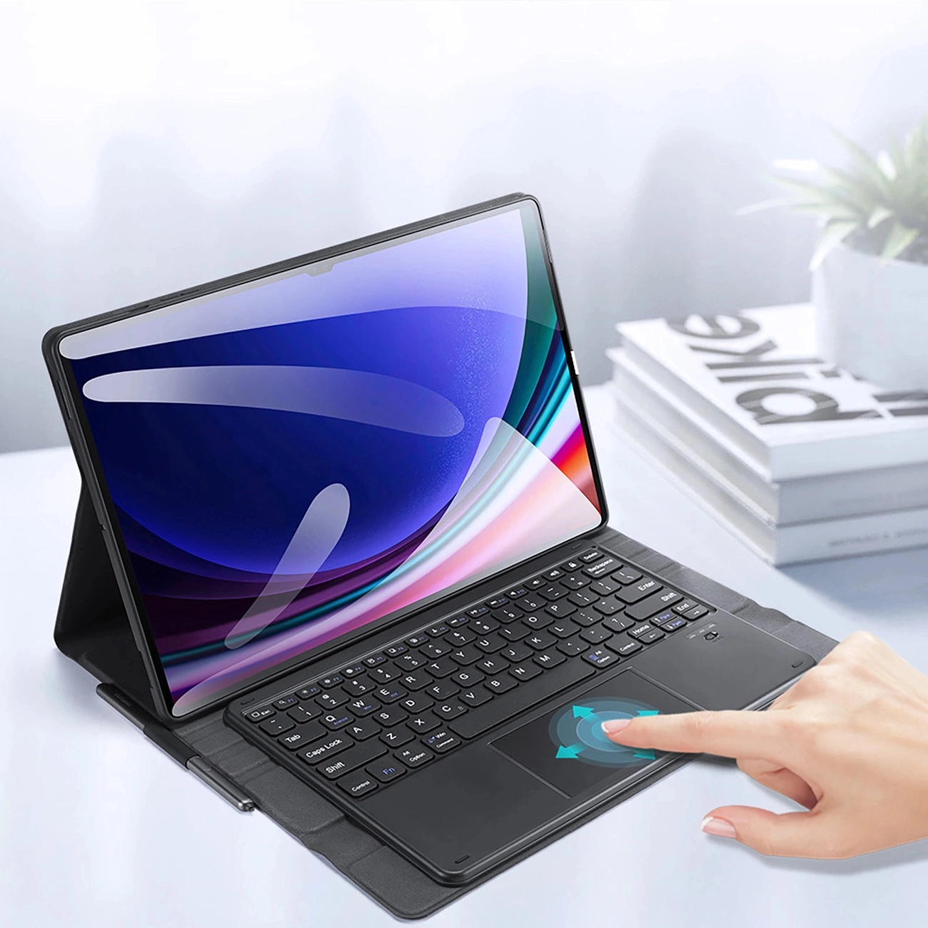 Un tablet con custodia tastiera e touchpad su una scrivania, una mano tocca il trackpad.